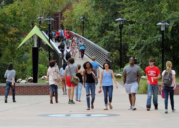 Students crossing bridge into Alumni Plaza